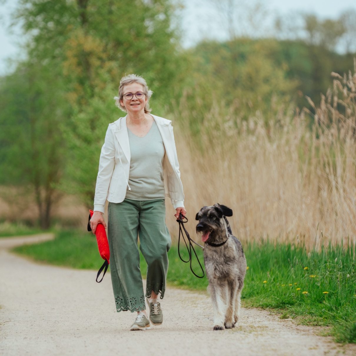 Dorothea trägt ein Spielzeug in der Hand und macht einen Spaziergang mit ihrer Hündin Martha