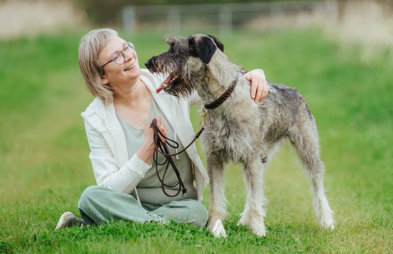 Dorothea Brandes sitzt auf einer grünen Wiese und schaut ihre Therapiehündin an